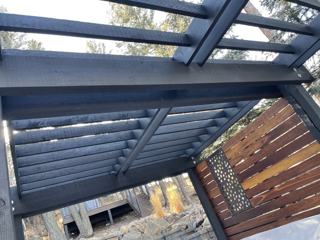 A metal structure with a wooden roof and a black frame.