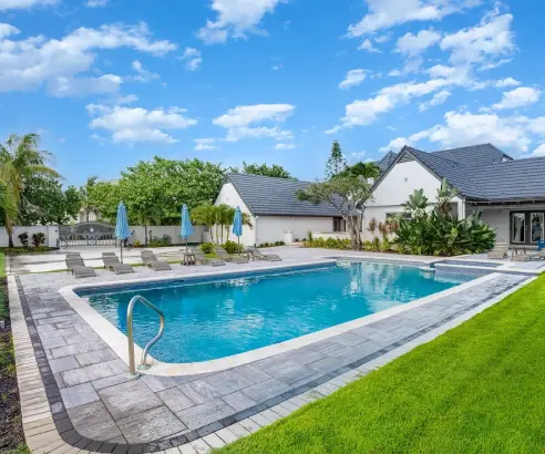 A swimming pool with chairs and umbrellas in the background.