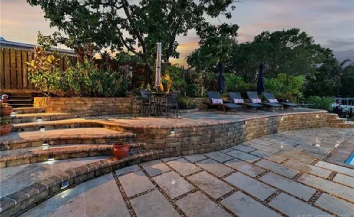 Illuminated pool patio with lounge chairs.