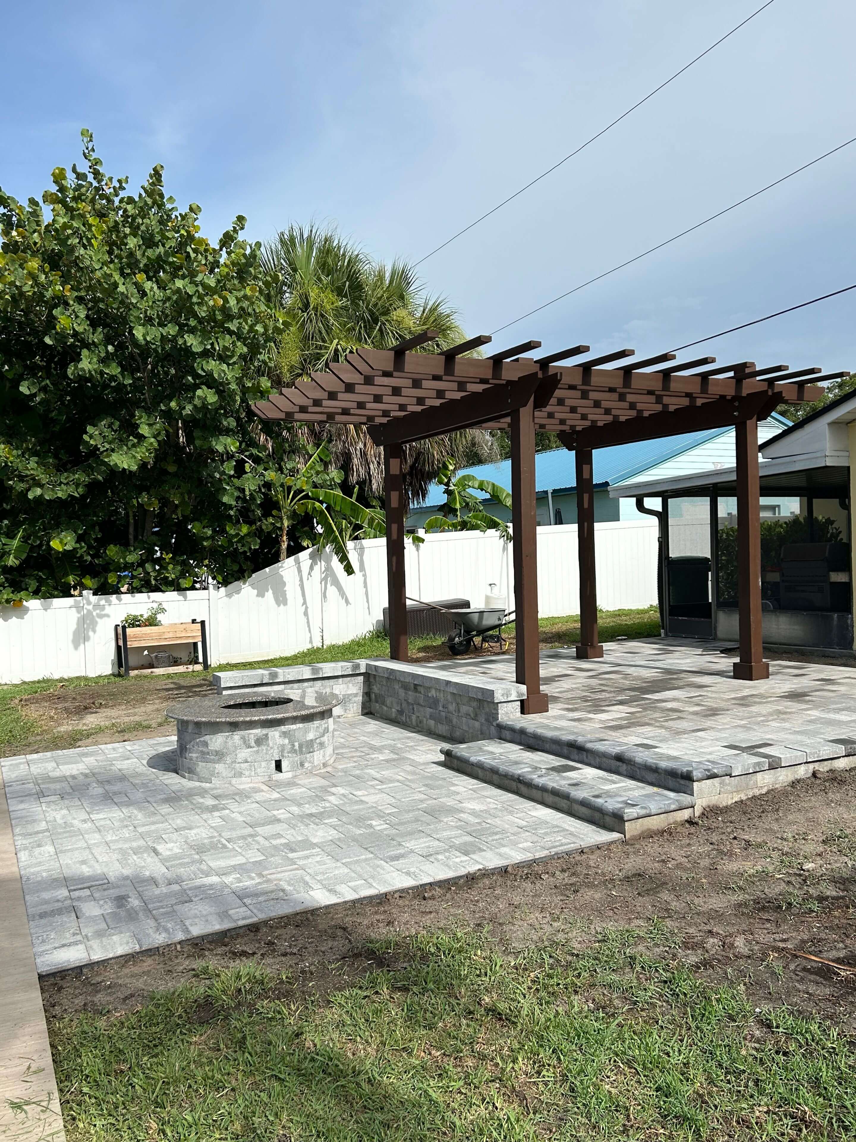 Here's an alt tag for the image: Backyard patio with pergola and fire pit.