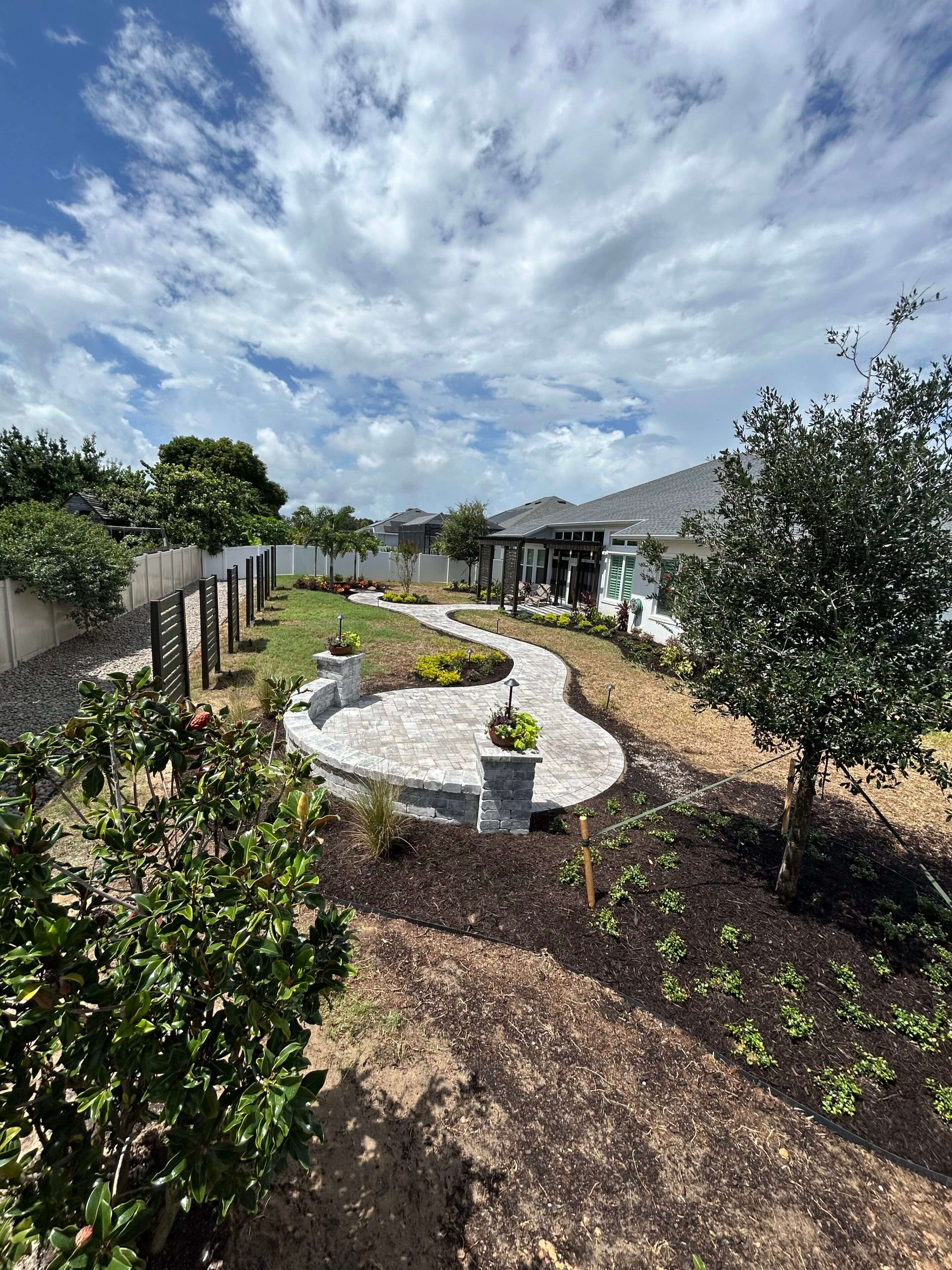 Curving stone pathway, landscaped backyard.