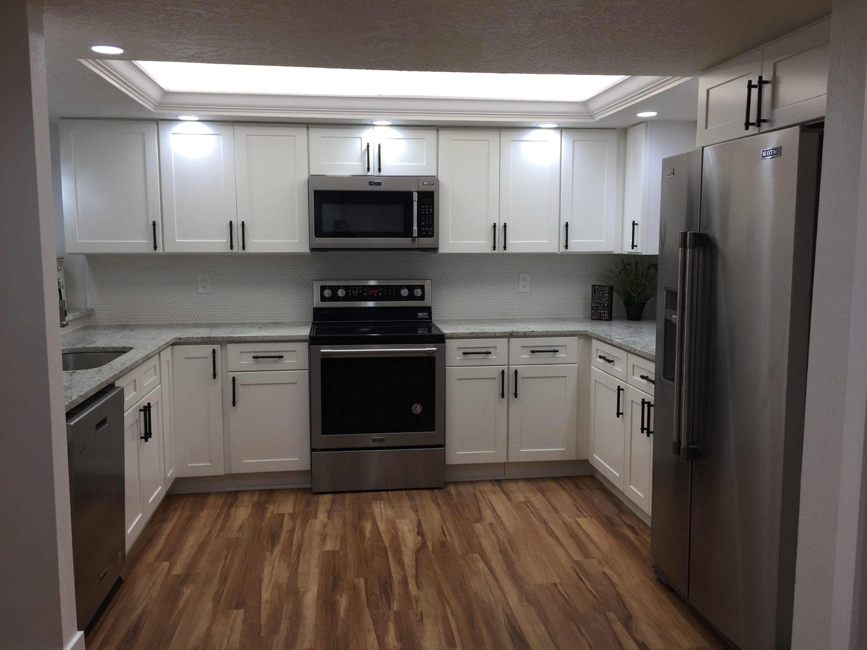 Modern white kitchen with stainless steel appliances.